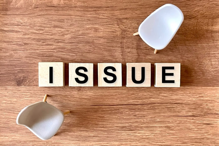 木製のテーブルに並んだ問題という文字とミニチュアの椅子