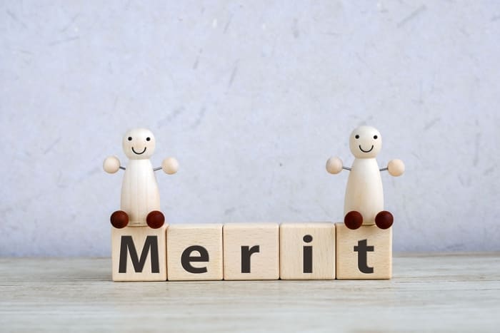 メリットと書かれた積み木の上に立つ人形