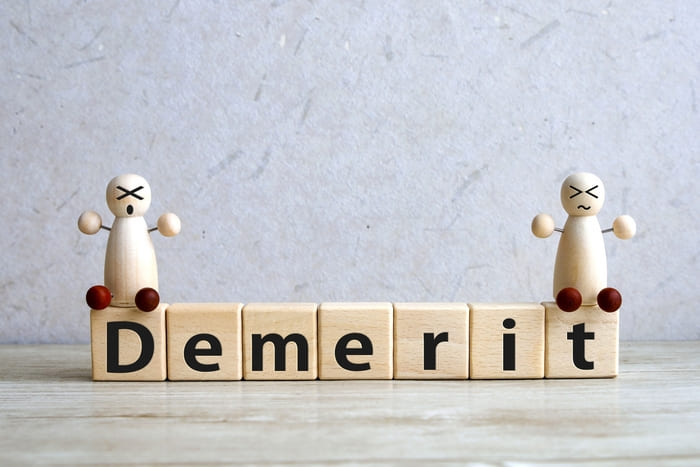 デメリットという文字が書かれた積み木と困った顔の人形