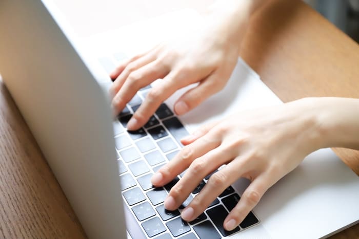 パソコンのキーボードを打つ手の写真