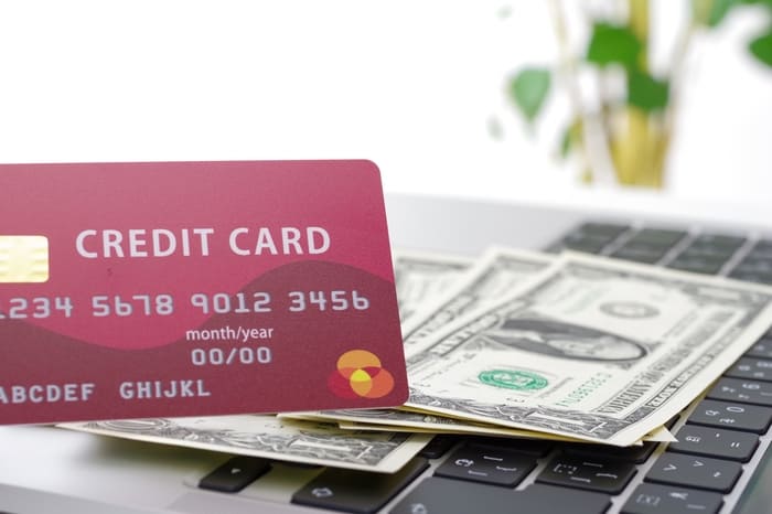クレジットカードとドル紙幣が載ったノートパソコン