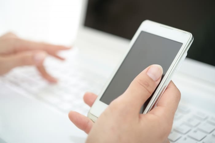 パソコンで文字を打ちながらスマホを持つ手