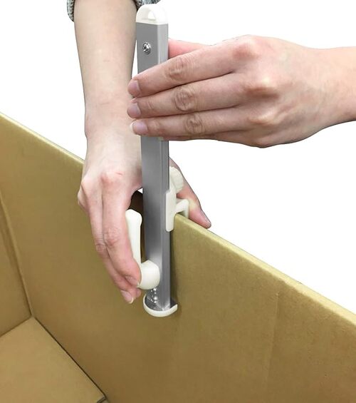 段ボール箱に引っ掛け金具を取り付ける人の手